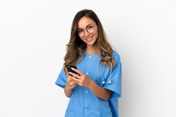 Young surgeon doctor woman over isolated white wall sending a message with the mobile