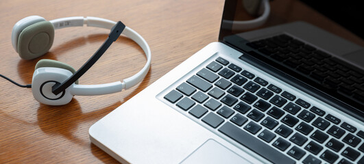 Home office, headset on a laptop, wooden table. Call center, customer support, help desk
