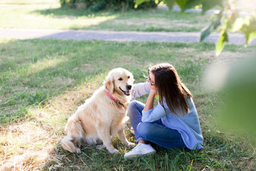 Dog and woman sit and hug in park. Girl and labrador retriever happy together