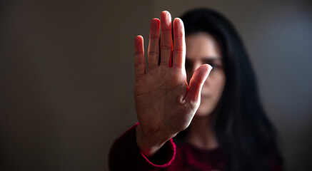 Stop violence against women. Young woman with raised hand for dissuade, black background, space