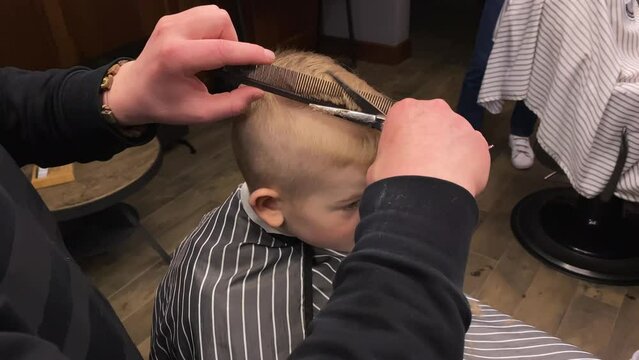 Master cuts a little boy's hair in a barbershop