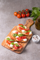 Tomato, basil and cheese fresh made caprese bruschetta. Italian tapas, antipasti with vegetables, herbs and oil on grilled ciabatta and baguette bread. Sandwich.