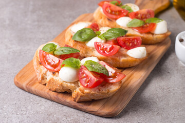 Tomato, basil and cheese fresh made caprese bruschetta. Italian tapas, antipasti with vegetables, herbs and oil on grilled ciabatta and baguette bread. Sandwich.