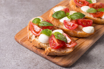 Tomato, basil and cheese fresh made caprese bruschetta. Italian tapas, antipasti with vegetables, herbs and oil on grilled ciabatta and baguette bread. Sandwich.