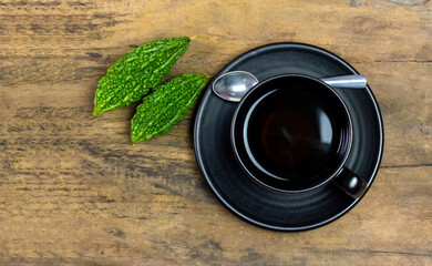 Bitter gourd or bitter melon tea in ceramic cup on rustic wooden background, top view.