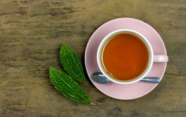 Bitter gourd or bitter melon tea in ceramic cup on rustic wooden background, top view.