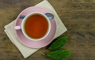 Bitter gourd or bitter melon tea in ceramic cup on rustic wooden background, top view.