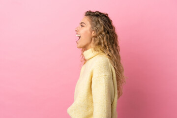 Young blonde woman isolated on pink background laughing in lateral position