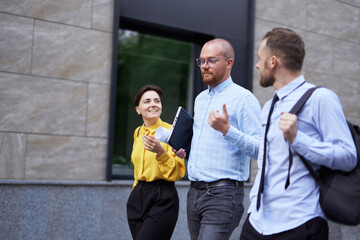 Business people brainstorming or discussing project outdoor walking. Three white collar workers in...