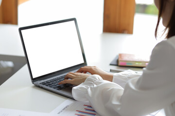 Fototapeta premium Thinking woman working on laptop with blank screen for copy space on office desk.