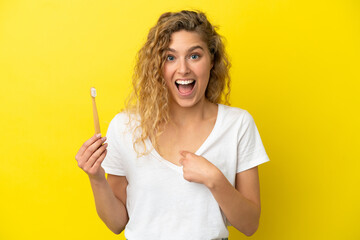 Fototapeta Young caucasian woman holding a brushing teeth isolated on yellow background with surprise facial expression obraz