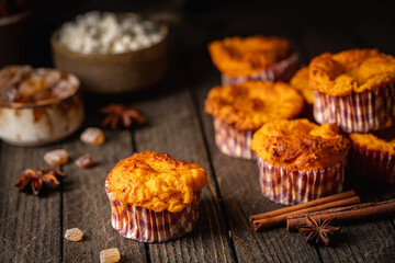 Sweet homemade cottage cheese muffins with pumpkin on dark wooden background