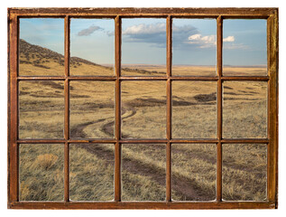 dirt ranch road in prairie in northern Colorado, early spring scenery as seen from a vintage sash window