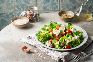 Classic vegetable salad with fresh olives, tomatoes, cucumbers, greek cheese feta and olive oil on gray background.