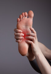 Foot pain in arch. Woman holding leg with red point closeup. Plantar fasciitis, inflammation,...