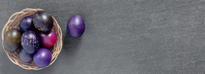 Lots of bird nests with painted Easter eggs on a dark tabletop. Holiday greeting card. Concept creative banner