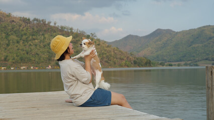 Asia woman people enjoy staycation pet owner getaway good time day with small puppy dog lover sit relax happy care hug and kiss cute friend at rural calm lake pier with blue sky in nature trip life.