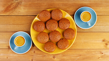 Freshly baked homemade cupcakes and two cups of coffee espresso on wooden table. Top view.
