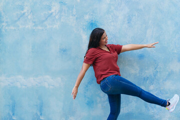 Latina woman with long hair standing outdoors in front of wall