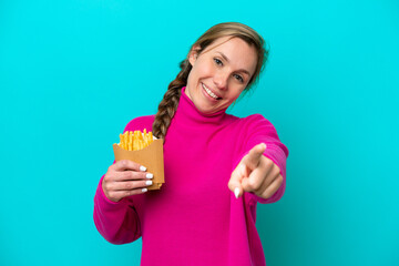 Young caucasian woman holding fried chips isolated on blue background pointing front with happy expression