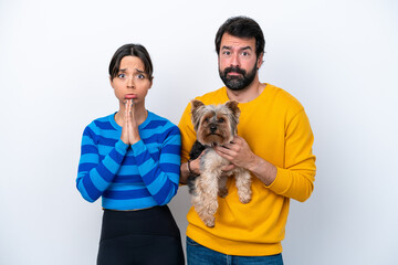 Obraz premium Young hispanic woman holding a dog isolated on white background pleading