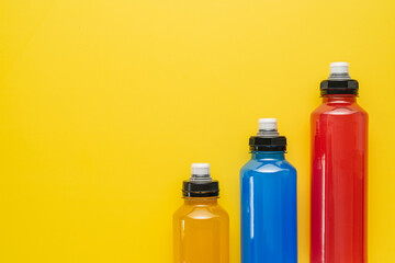 Isotonic energy drink. Bottle with blue and yellow transparent electolytes liquid, sport beverage on a yellow background. It usually contains salt and sugar and maintains optimal hydration