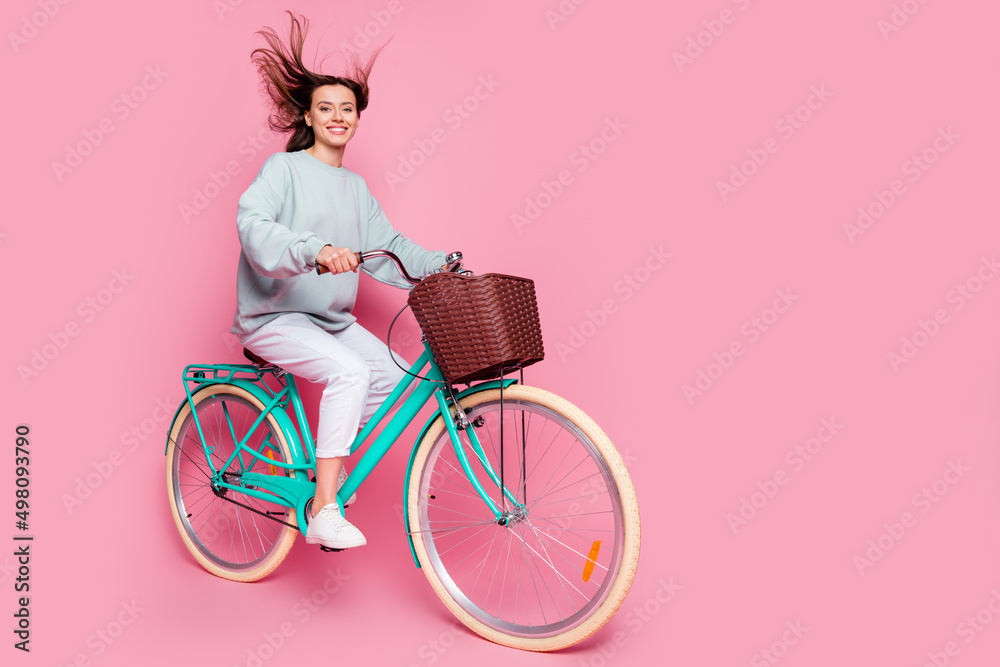 Poster full size profile side photo of young girl adventure hobby ride bicycle isolated over pink color bac