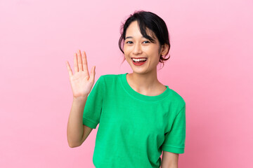 Young Vietnamese woman isolated on pink background saluting with hand with happy expression