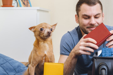 Happy young man with his adorable small dog Toy Terrier, man holds passports in his hands.