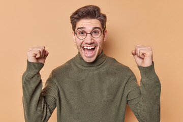 Happy adult European man wins and celebrates something makes fist bump exclaims yes achieves goal...
