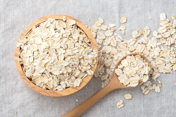 Rolled oat, raw oatmeal with spoon in wooden bowl