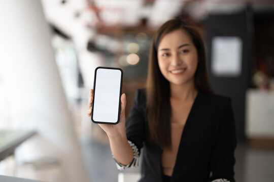 Mockup image of a beautiful business asian woman showing mobile phone with blank white screen