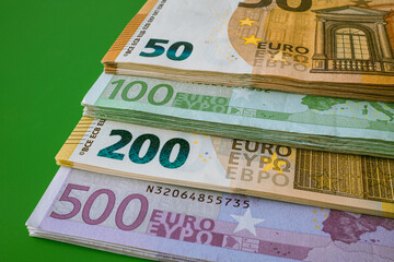 A stack of different euro banknotes on a green background