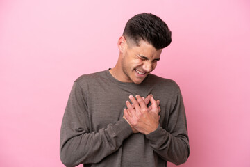 Young caucasian man isolated on pink background having a pain in the heart