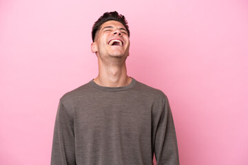 Young caucasian man isolated on pink background laughing