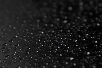 Water drops on the surface covered with foil. Surface tension.