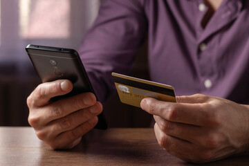 Man holding credit card making e bank online payment. Consumer paying for purchase using smartphone technology.