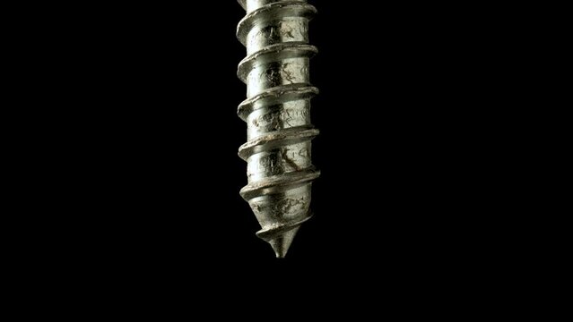 Sharper of a steel screw or metal bolt rotating on isolated black background. Helix thread closeup. Fastening tools for repair or construction in workshop or hardware shop. Slow motion ready 59.97fps.