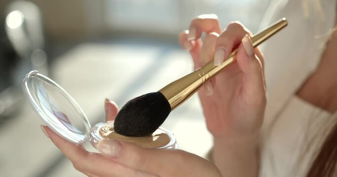 Beautiful girl doing makeup with a brush in studio