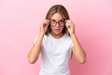 Little caucasian girl isolated on pink background With glasses and surprised expression