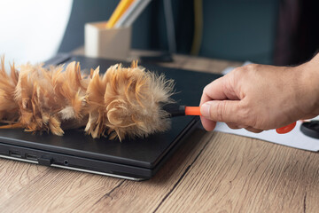 Use a feather duster to clean the notebook computer.