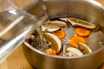 The cook prepares mushroom soup from porcini mushrooms, carrots and herbs