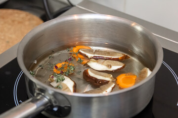 The cook prepares mushroom soup from porcini mushrooms, carrots and herbs
