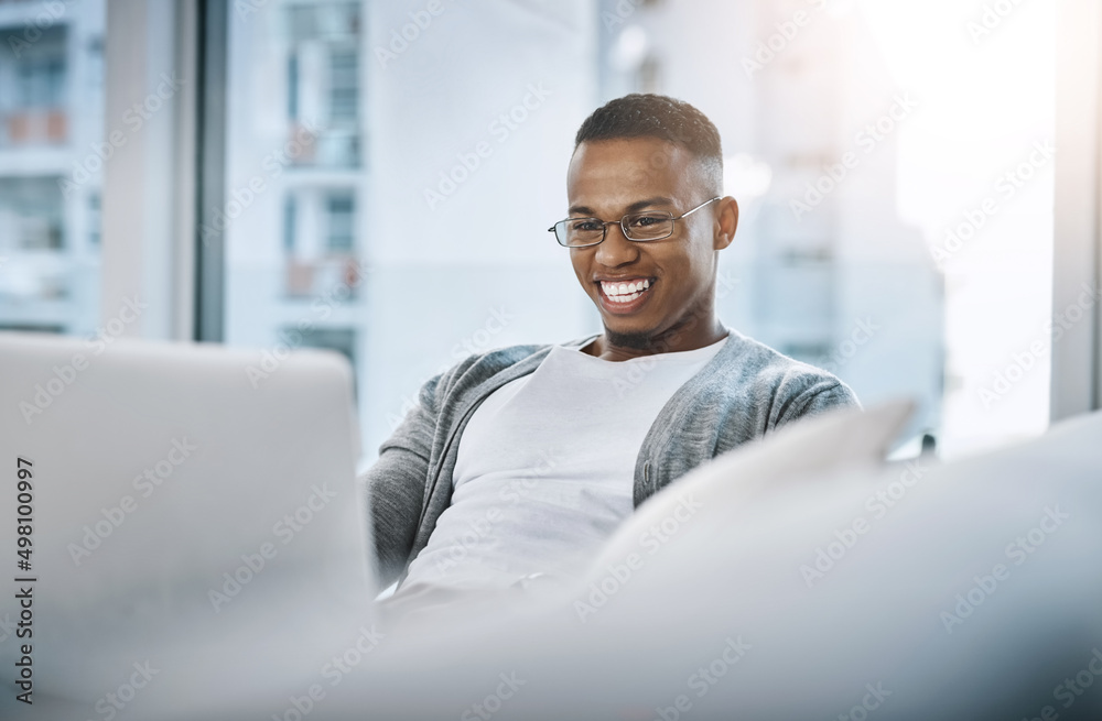 Poster this is what i actually do on my off days. shot of a handsome young man using his laptop while sitti