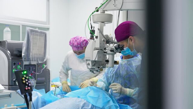 Ophthalmology operation in modern clinic. Medical team performing eye surgery using advanced equipment.