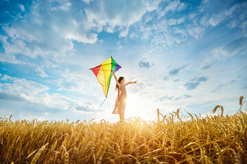 Little girl plays with a kite among ripe golden wheat field. Investing in the future, agriculture...