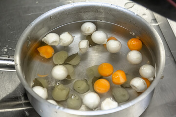 The cook cooks balls cut out of carrots and potatoes in a saucepan