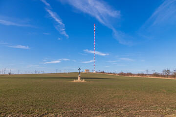 Spring landscape with high voltage poles. In the background a television transmitter and in the foreground the Passion. The sky is blue. - obrazy, fototapety, plakaty