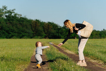 Cute little baby boy giving his mom flowers during a trip in a countryside