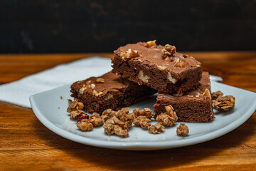 Homemade chocolate brownie squares with pecan pieces served on a white plate. Natural, healthy food concept.